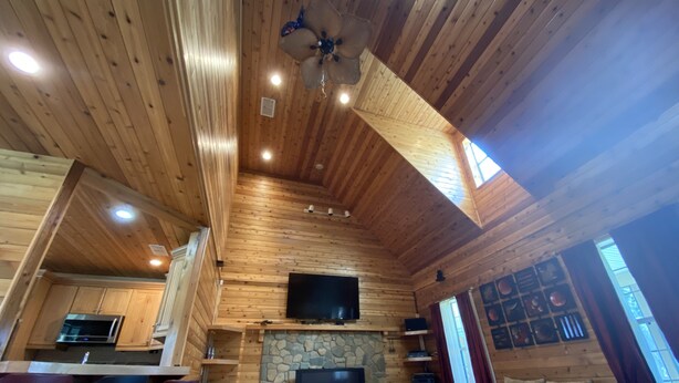 A wooden interior with a stone fireplace, a flat-screen TV, and a dining area with bar stools. - Springfed Canal on Lake George/ Large 4 Bedroom house on water/Boat Ramp/Hot Tub (SaltSprings)