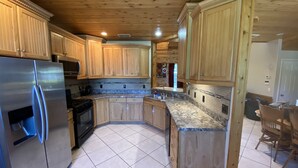 A kitchen with wooden cabinets, a stainless steel refrigerator, and a granite countertop.