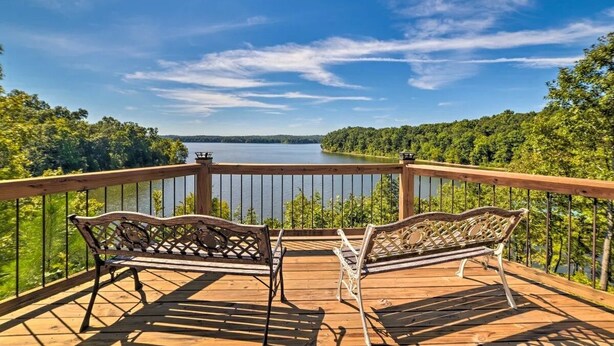 A wooden deck with two wicker chairs overlooking a lake surrounded by trees. - Lynnhurst Resort Motel #9...Dog Friendly Jet Ski Rentals on site (Murray)