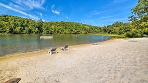 A beach with clear water, a boat, and lounge chairs. - Lynnhurst Resort Motel #9...Dog Friendly Jet Ski Rentals on site (Murray)