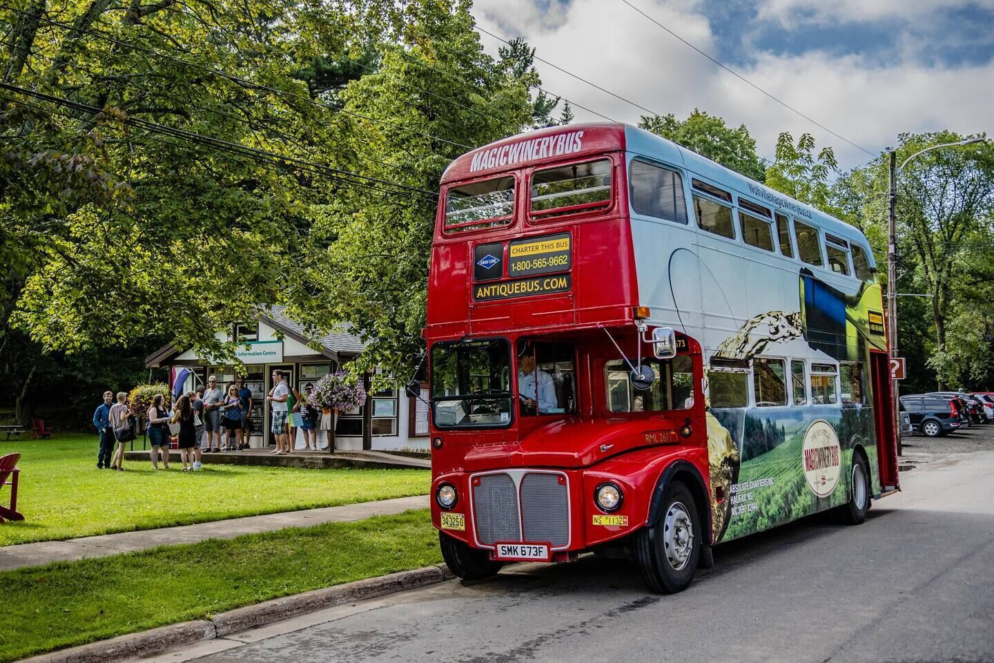 Un autobus a due piani rosso con la scritta "MAGIC WINERY BUS" e "ANTIQUEBUS.COM" sul fianco.