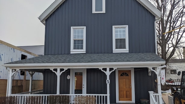 A two-story house with a porch, a wooden door, and a number '5' sign. - Flamingo Suite (Downtown Wolfville) (Wolfville)