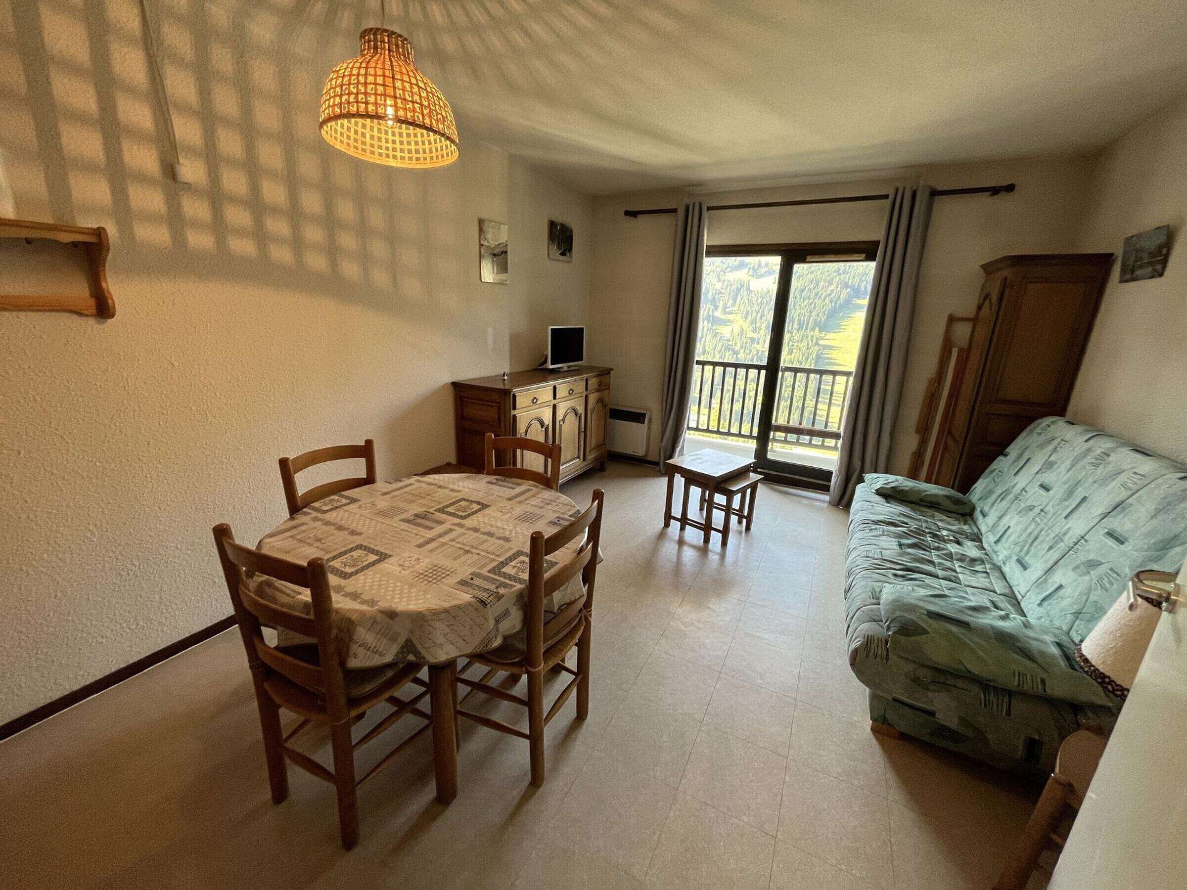 Een gezellige woonkamer met een eethoek, een bank, een televisie en een balkon met uitzicht.