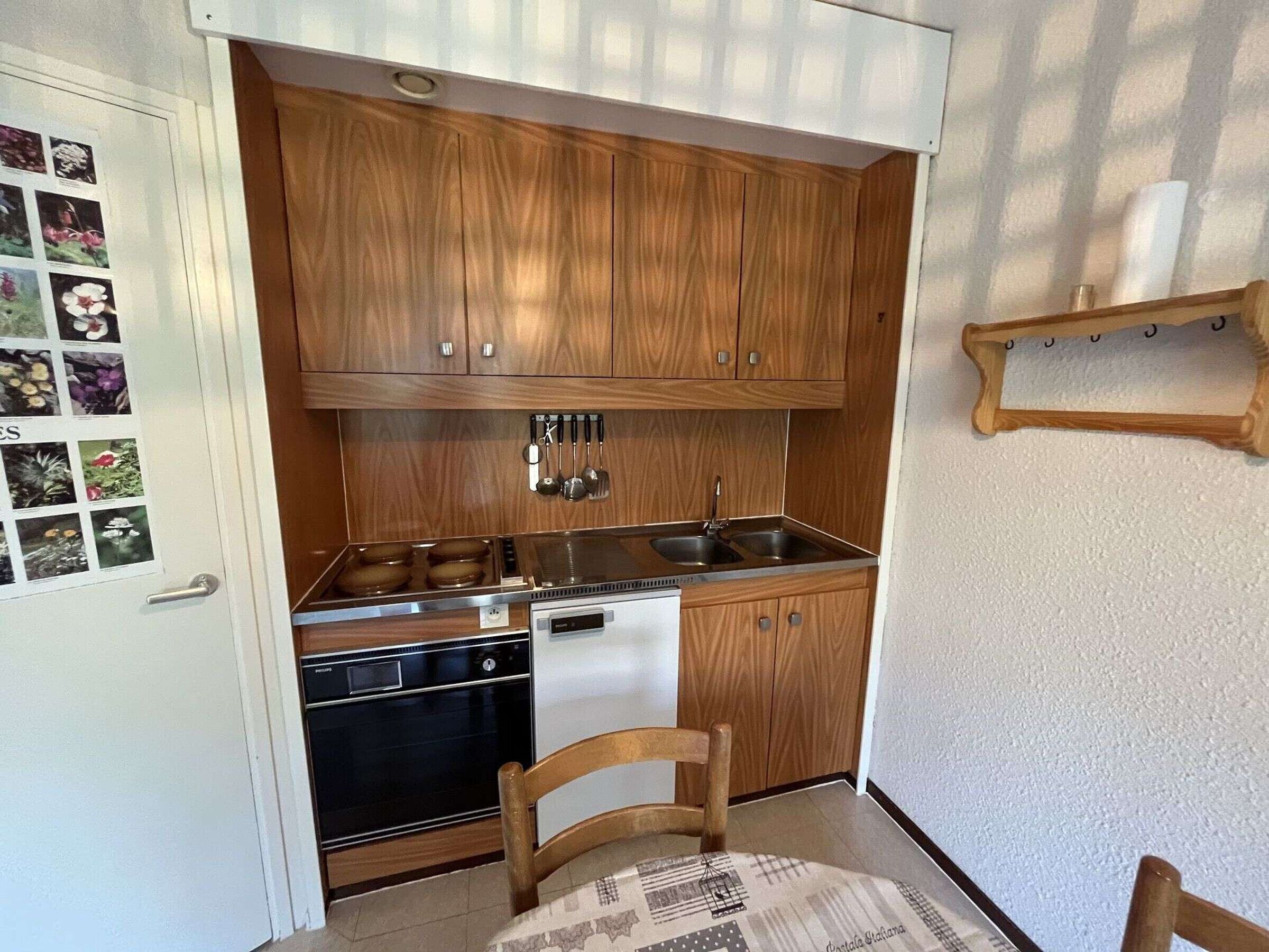 A compact kitchen with wooden cabinets, a dishwasher, and a sink.