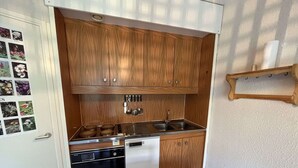 Une cuisine de taille réduite, dotée de meubles en bois, d’un lave-vaisselle et d’un évier.