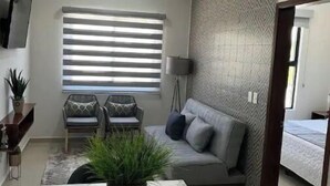 Una sala de estar moderna con un sofá, una mesa de comedor y una planta en maceta.