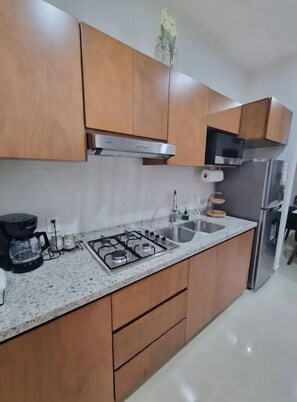 Een moderne keuken met houten kastjes, een rvs afzuigkap, een ingebouwde gootsteen en een koelkast.