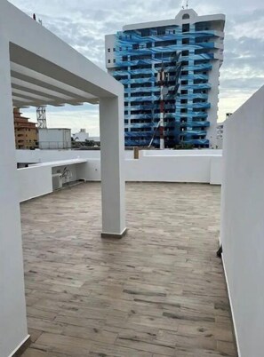 Een terras op het dak met uitzicht op een blauw gebouw in aanbouw.