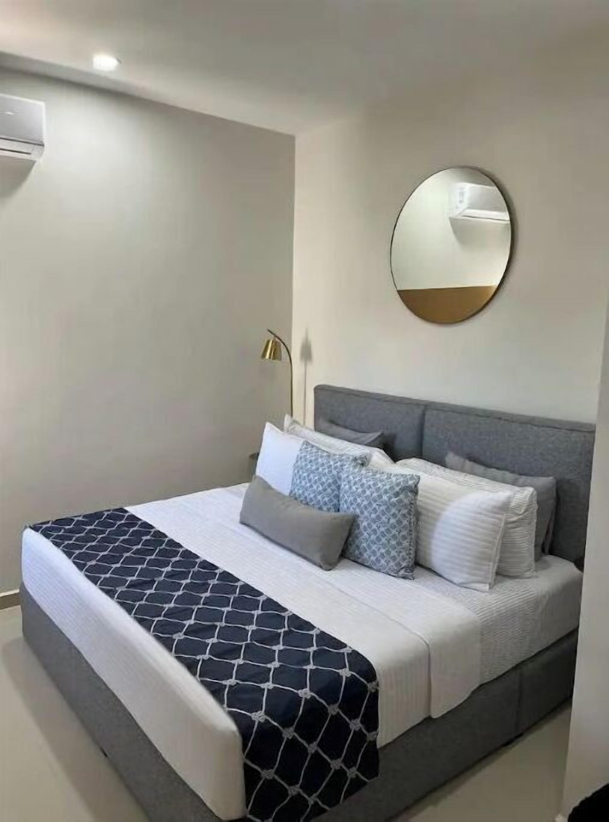 Ein Schlafzimmer mit einem Bett, einem runden Spiegel und einer Lampe.