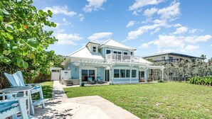 A two-story house with a covered patio and a backyard with a lawn and outdoor furniture. - Sea Watch: 4B/4B Direct Oceanfront Home with Pool Near Downtown Cocoa Beach (Cocoa Beach)