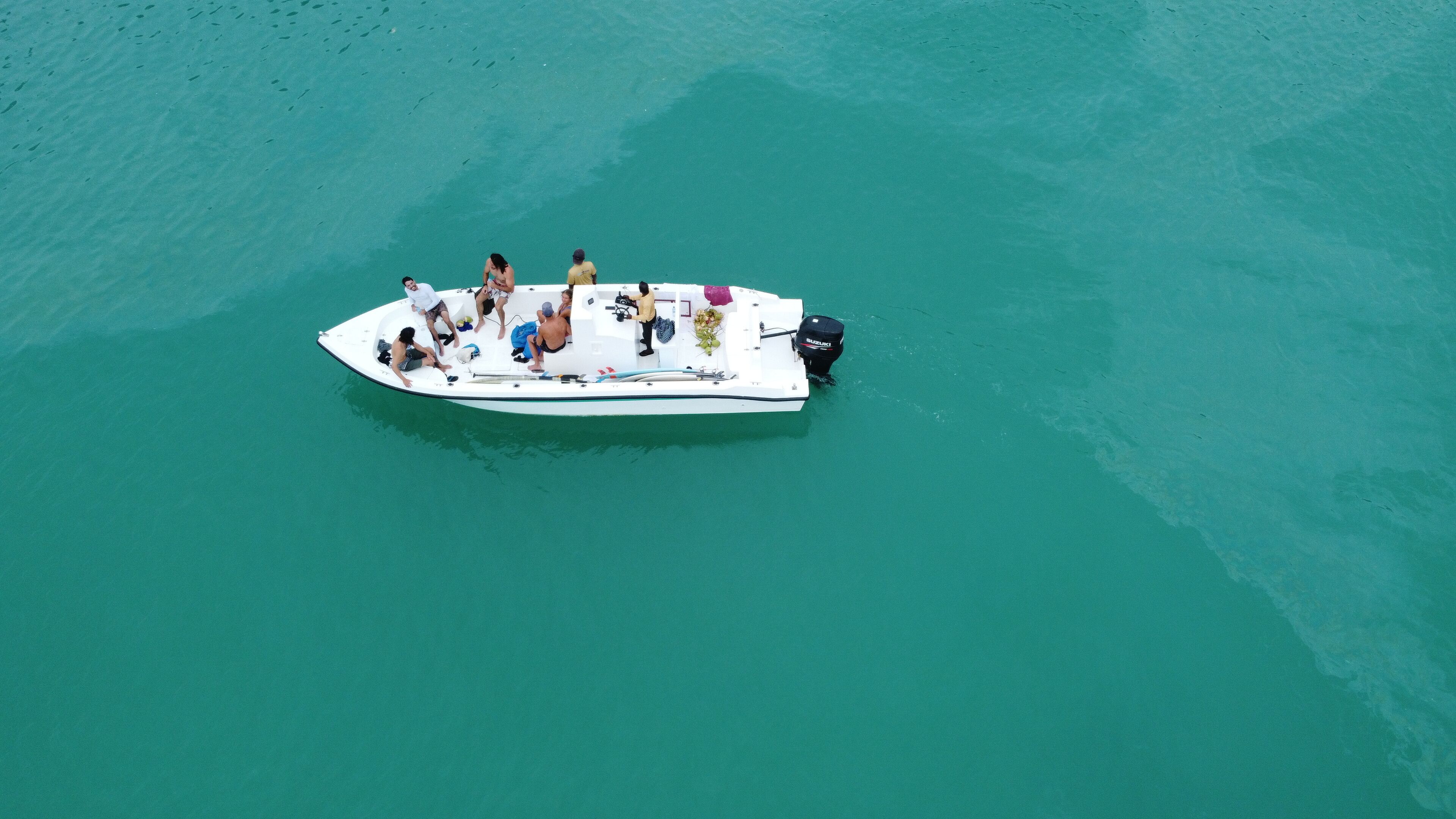 A small boat with people on it, floating on clear turquoise water.
