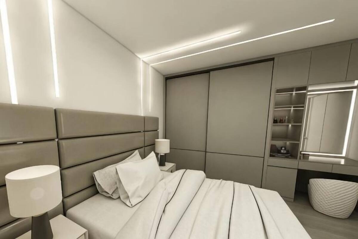 A modern bedroom with a bed, bedside tables, a lamp, a mirror, and built-in storage.