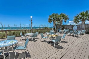 Une terrasse extérieure avec des tables et des chaises, une clôture en bois et des palmiers.