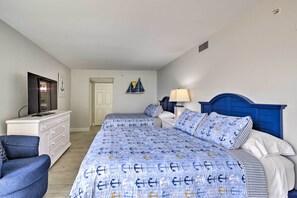 Une chambre à coucher comprenant un lit, une chaise, une commode, une lampe et un téléviseur.