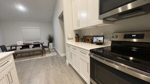 Una cocina moderna con armarios blancos, microondas integrado y horno de acero inoxidable.
