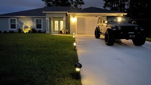 Una casa residencial con garaje, entrada para vehículos y una camioneta SUV estacionada.