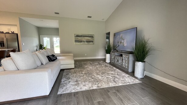 Una sala de estar moderna con un sofá modular, un televisor de pantalla plana y plantas decorativas.