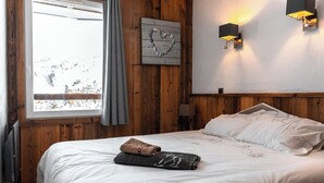 Een slaapkamer met een houten wandpaneel, een bed met witte beddengoed, een hartvormige decoratie en twee wandlampen.