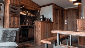 Een landelijke keuken met houten kastjes, een ingebouwde oven en een koffiehoek.