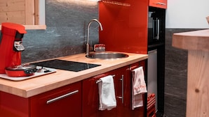 A modern kitchen with red cabinetry, a black microwave, and a stainless steel sink. - Immodreams - La Patinoire - Avoriaz (Avoriaz)