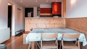 A compact kitchen with a wooden table and chairs, a built-in oven, and a red cabinet. - Immodreams - La Patinoire - Avoriaz (Avoriaz)