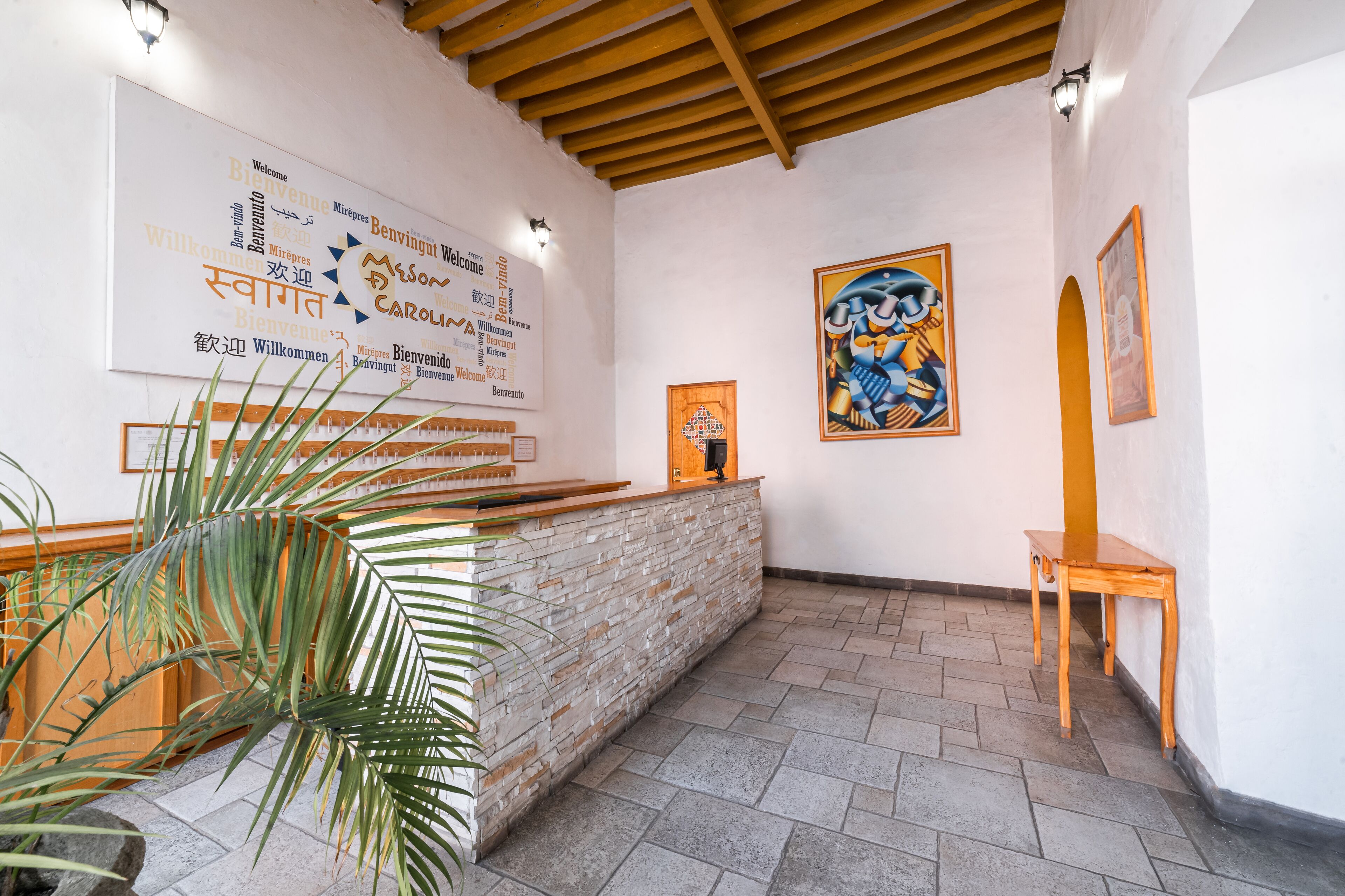 A reception area with a stone counter, wooden reception desk, and a wall with multilingual welcome signs.