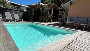 A rectangular swimming pool with a wooden deck surrounding it. - Chambre LES Pins (Mimizan)