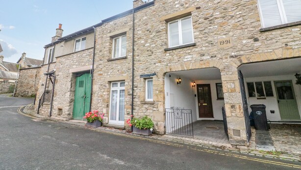 A stone building with a green door, numbered 1991, and a garage entrance. - No. 2 The Mews (Carnforth)