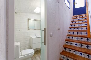 A bathroom with white tiles, a toilet, and a sink.