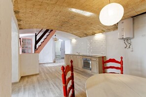 A kitchen with a wooden ceiling, white brick backsplash, and a red chair.