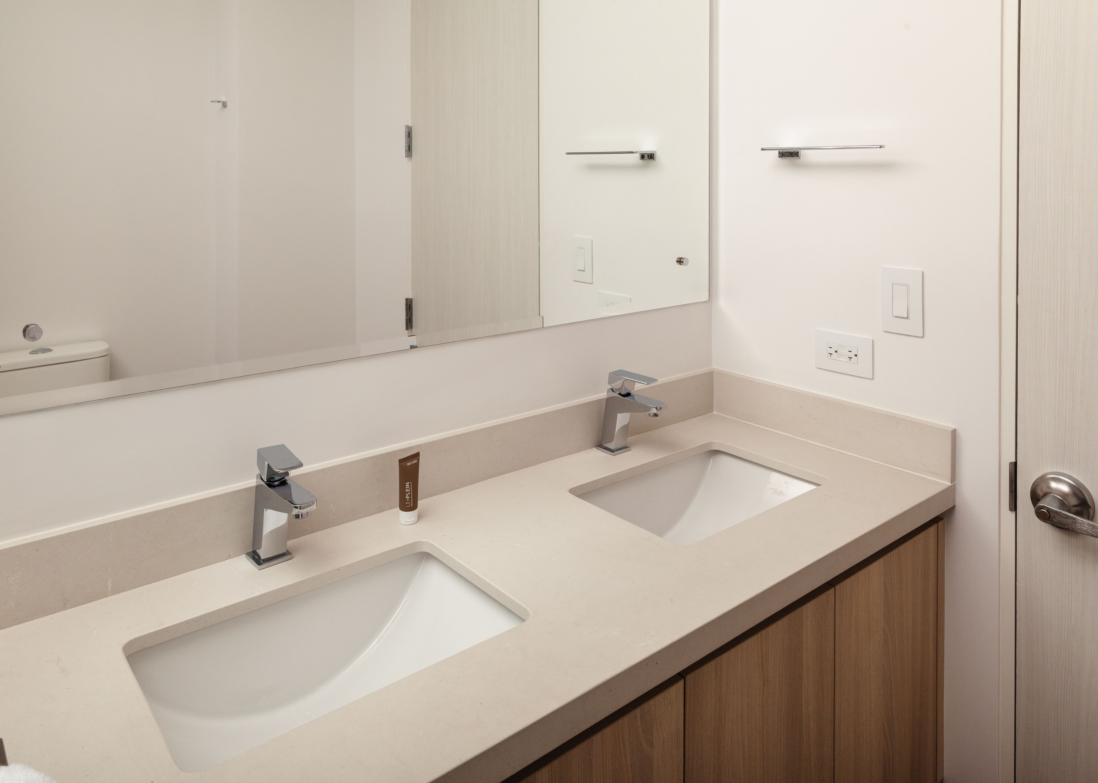 Une salle de bain avec deux lavabos, un miroir et un meuble en bois.