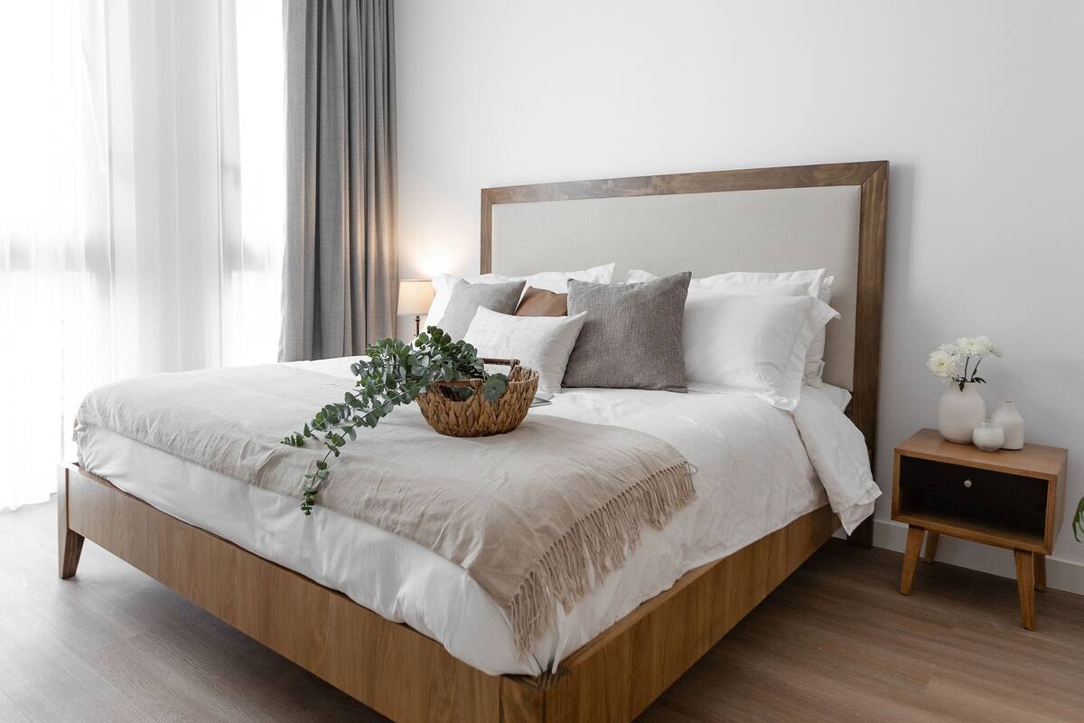 A modern bedroom with a wooden bed, a bedside table, and a wall-mounted air conditioner.