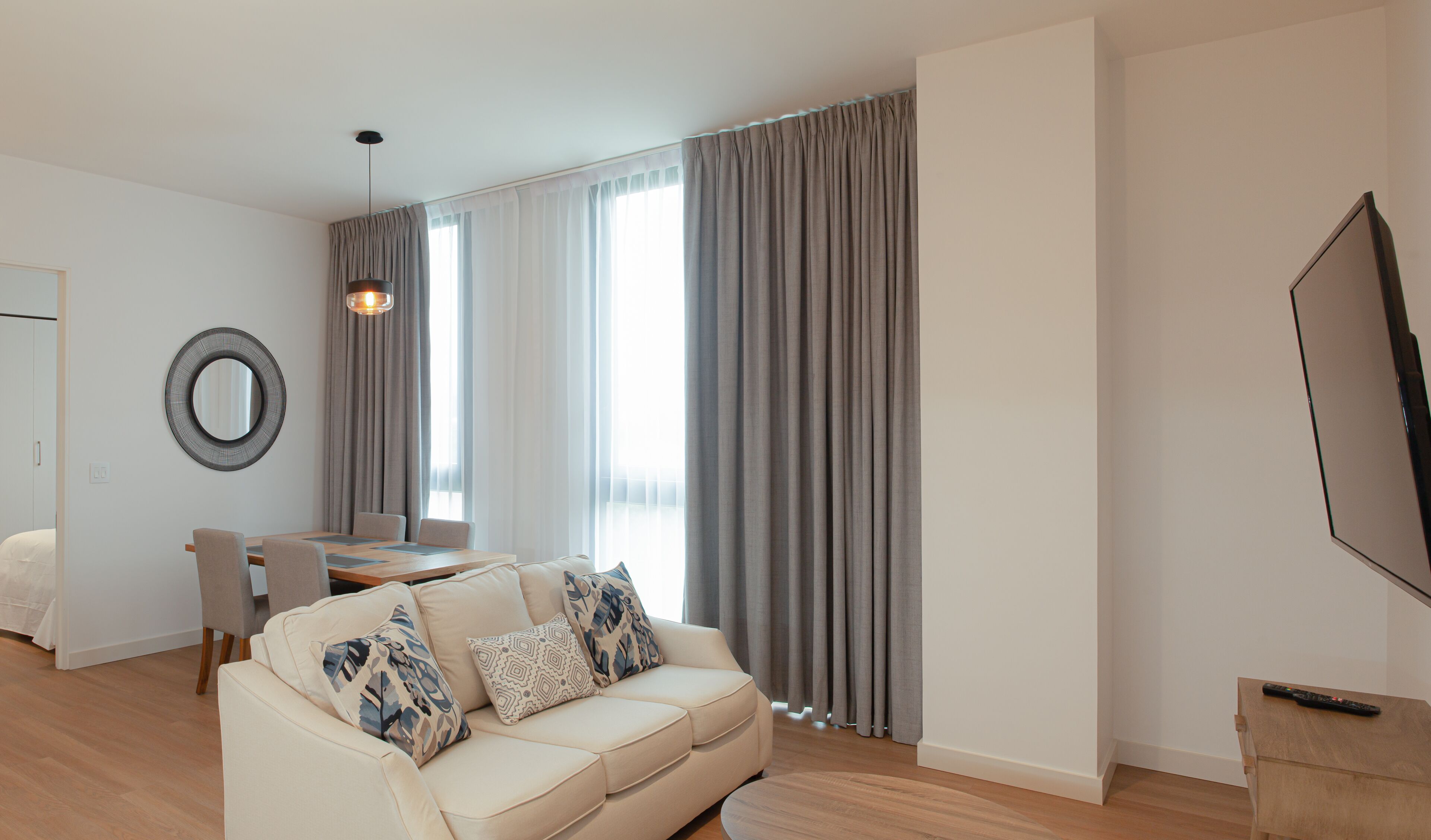 A modern living room with a sofa, a dining table, and a TV.