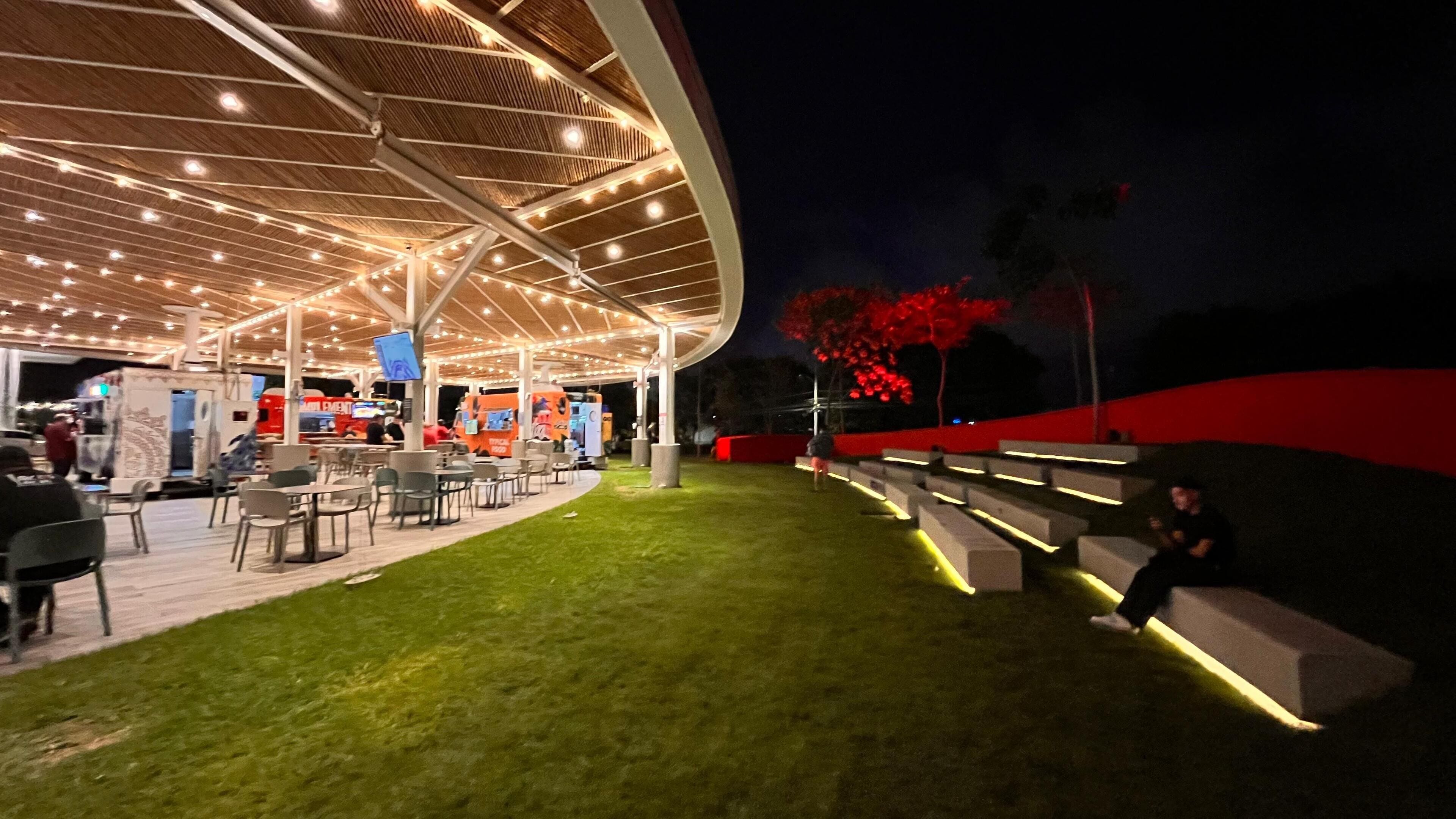 An outdoor seating area with tables and chairs, a covered section with a roof, and a red wall.
