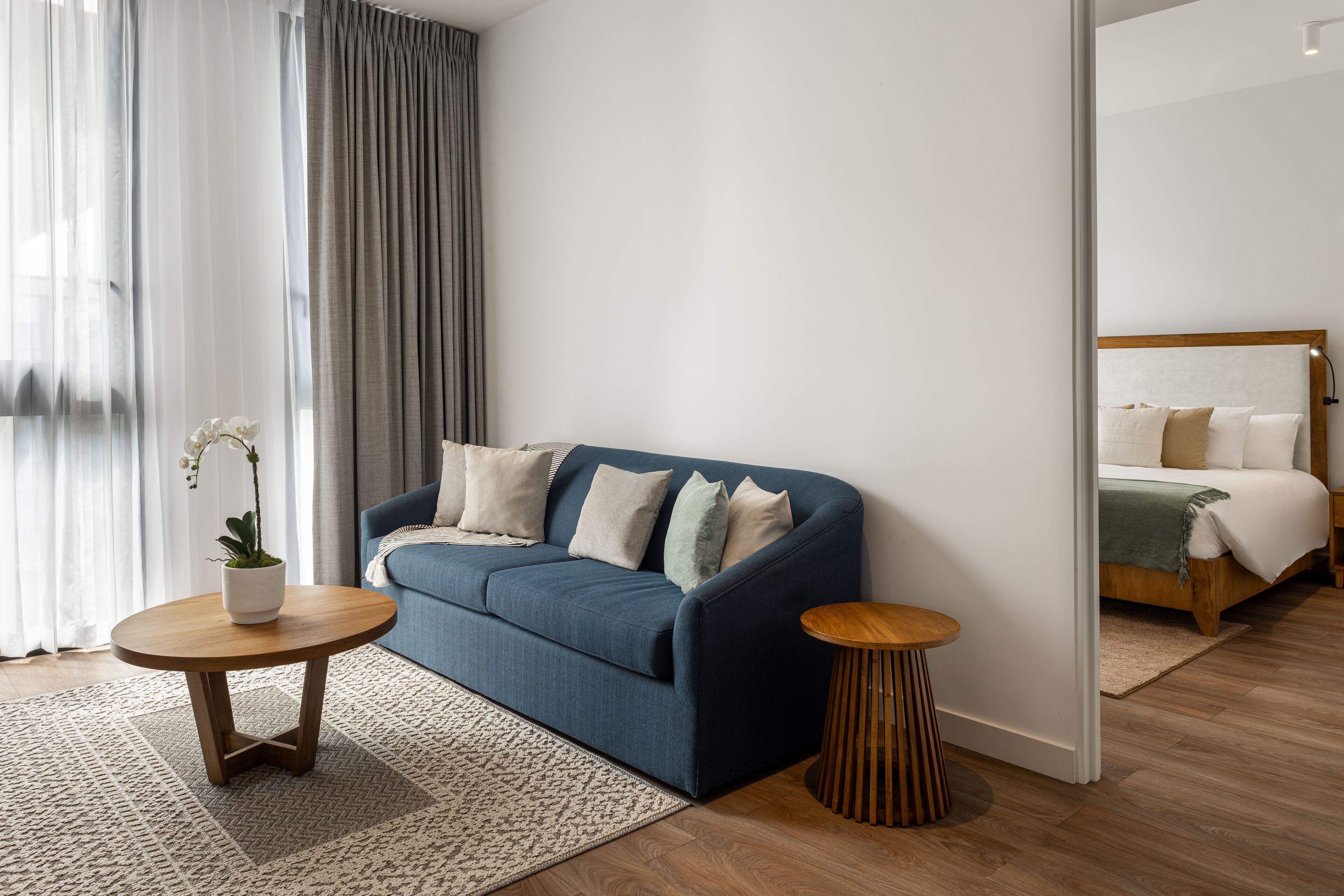 A modern living room with a blue sofa, a round wooden coffee table, and a small side table.
