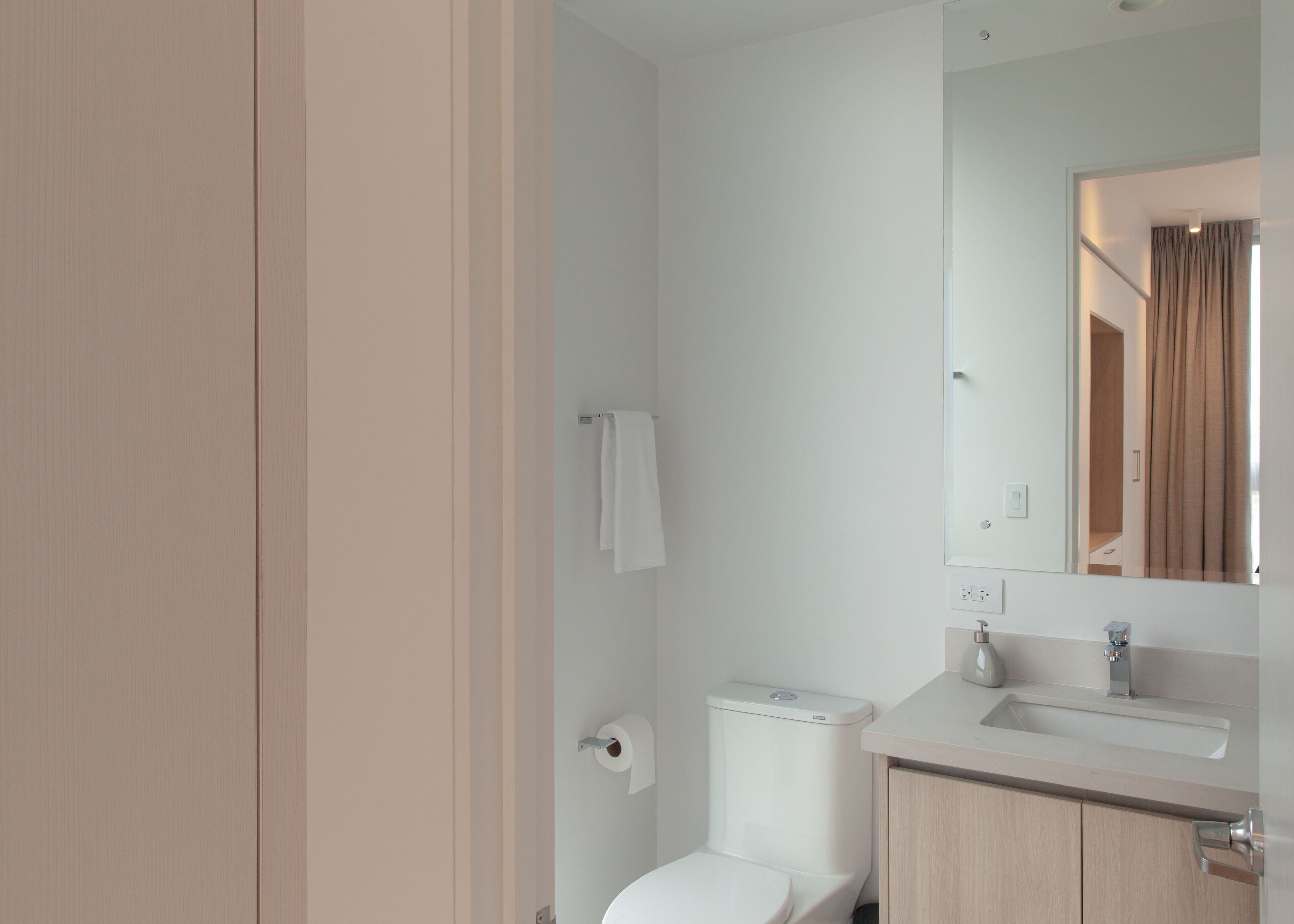 Un baño moderno con inodoro, lavamanos y espejo.