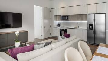 A modern living room with a sofa, a flat-screen TV, and a potted plant.