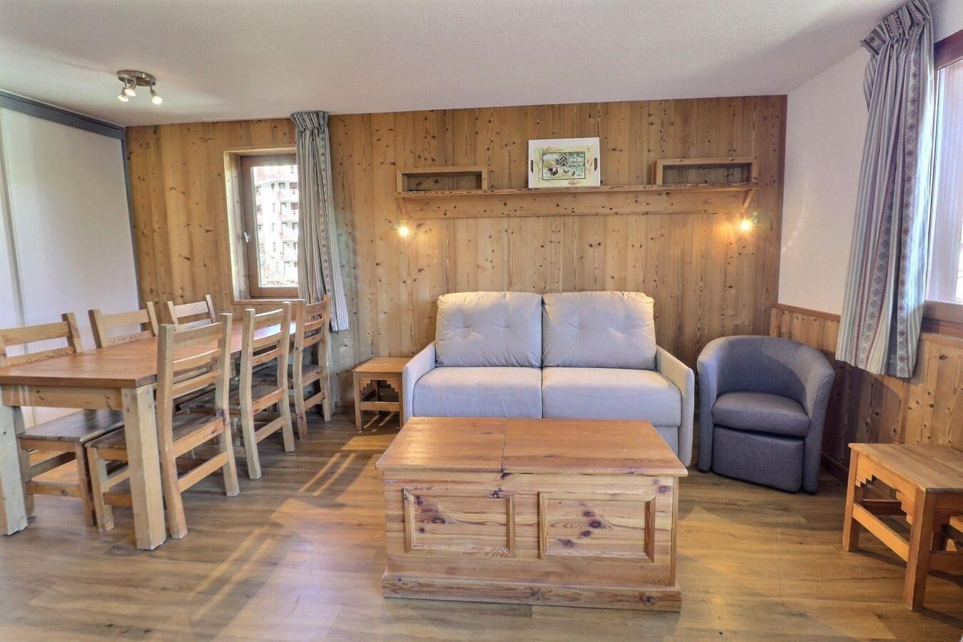 Un salon chaleureux avec des murs en bois, un canapé, une table basse et un coin repas avec des chaises.