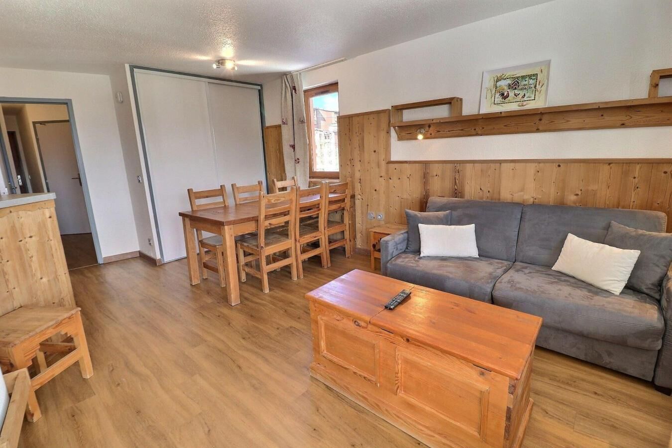 A cozy living room with a sofa, wooden coffee table, and a dining table with chairs.