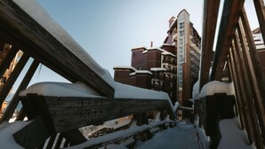 Un escalier en bois recouvert de neige mène à un immeuble à plusieurs étages doté de balcons.