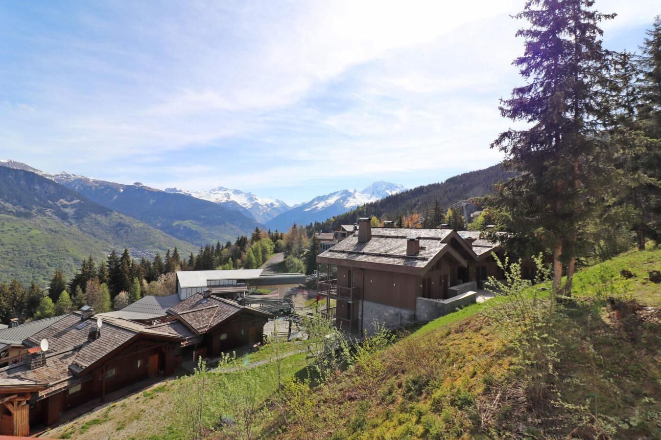 Een berghut met traditionele houten architectuur, een skilift en uitzicht op besneeuwde bergtoppen.