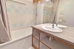 A bathroom with a bathtub, two sinks, a mirror, and a shower.
