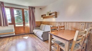 A wooden interior with a sofa, dining table, and chairs.