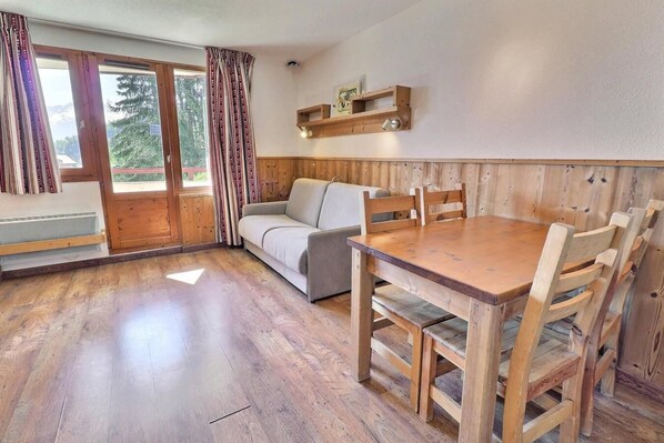 A wooden interior with a sofa, dining table, and chairs.