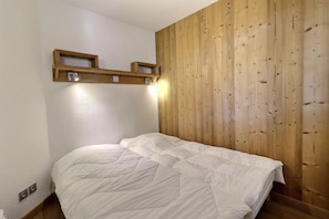 Une chambre à coucher avec une tête de lit en bois, un lit avec une literie blanche et une étagère au-dessus du lit.