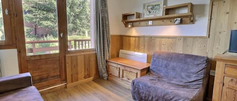 A cozy room with a wooden bench, a cushioned chair, and a desk.