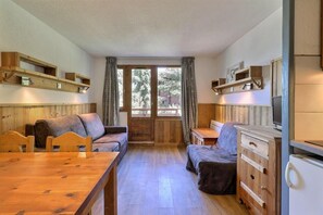 Un interior de cabaña acogedor, con una mesa de comedor de madera, dos sofás, un armario de madera y una televisión.