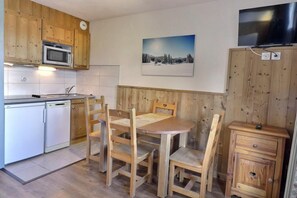 Une cuisine avec des meubles de rangement en bois, un four à micro-ondes, un évier et une table à manger avec des chaises.