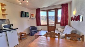 A compact living space with a kitchenette, a dining table, a sofa, and a chair. - 10m from ski slopes, 7th floor, balcony, ski locker, 25m², La Tania (Courchevel)
