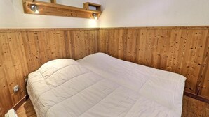 Een slaapkamer met een houten hoofdbord, een bed met witte beddengoed en een wandlamp.